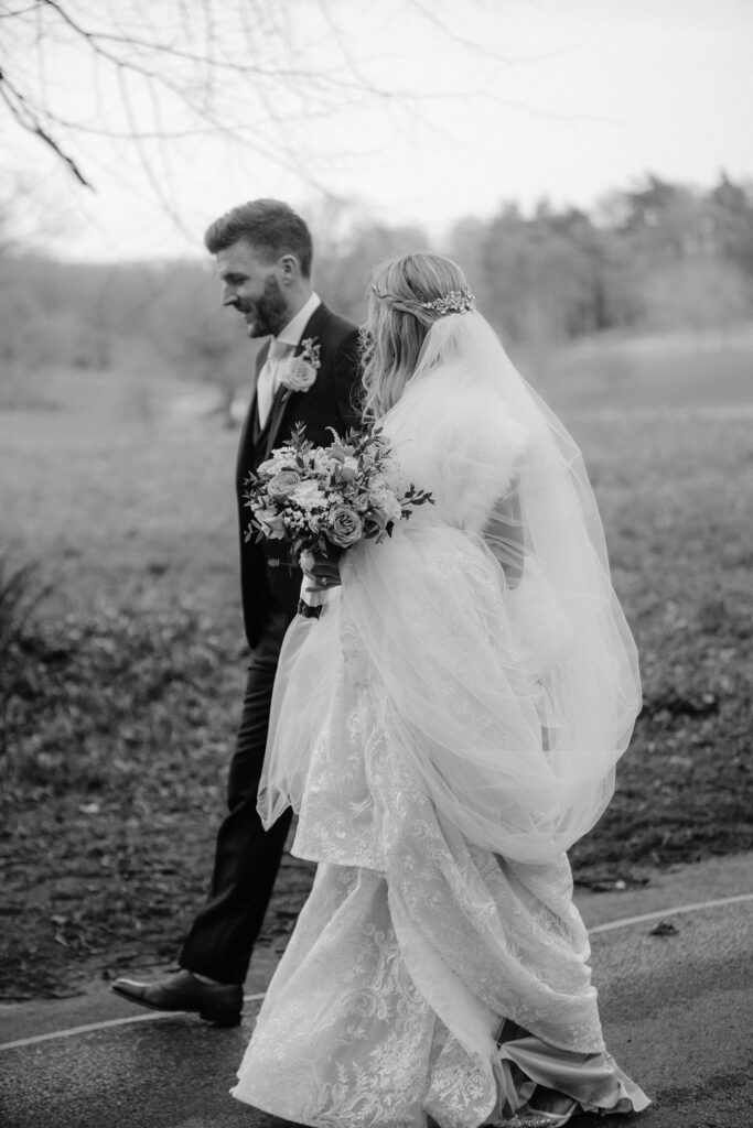 Bride and groom walking through Bowood Hotel grounds in black and white