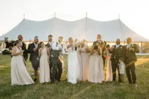 Bride and wedding party pop champagne in golden light outside marquee | Gloucestershire wedding photographer