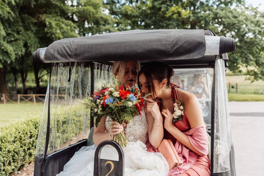 Bride and bridesmaid sharing joyful moment in buggy on the way to Callow Hall wedding ceremony.