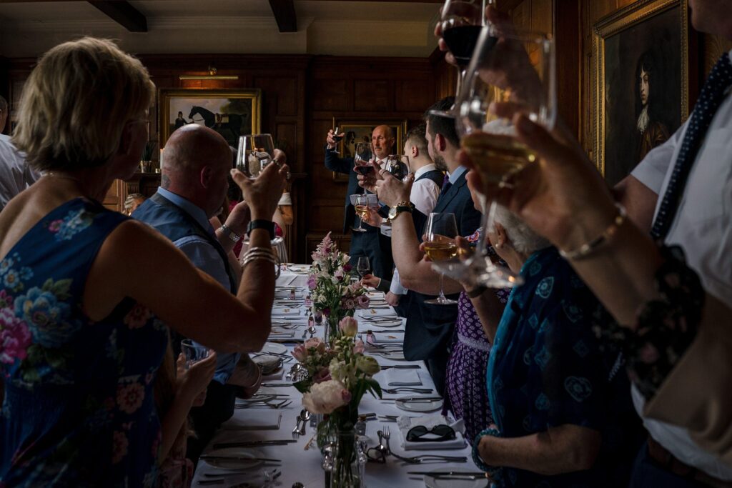 Guests raising glasses during a wedding toast at Burleigh Court Stroud