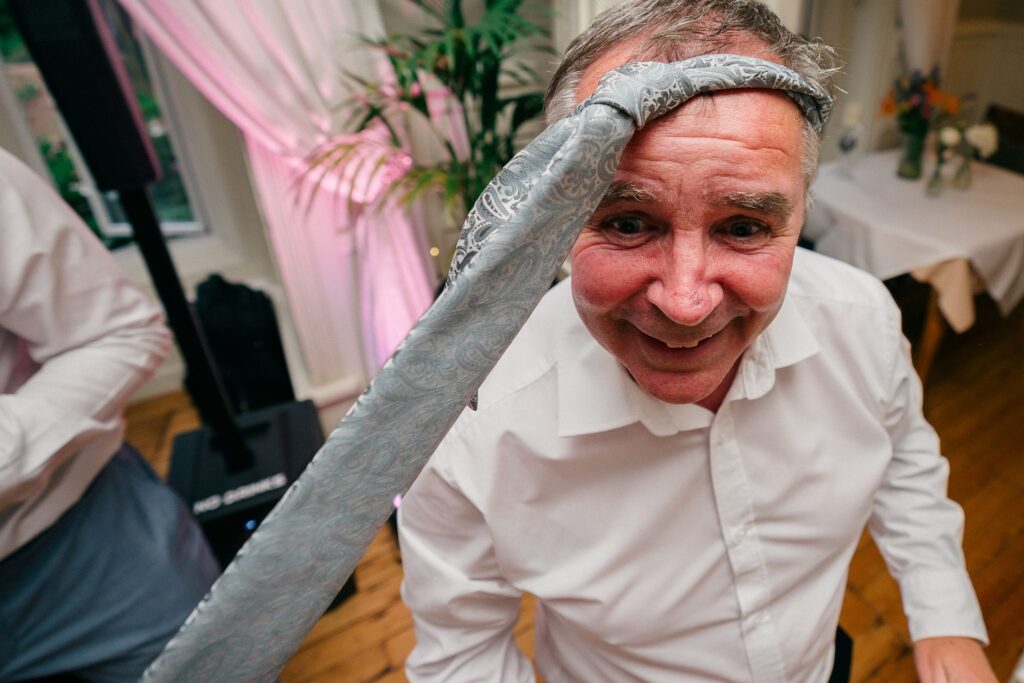 Guest dancing with a tie on his head during the Berwick Lodge wedding party