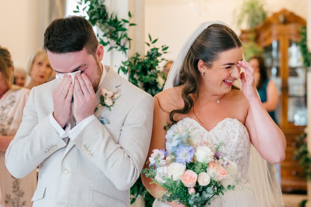 Bride and groom wiping happy tears during their emotional ceremony at Berwick Lodge