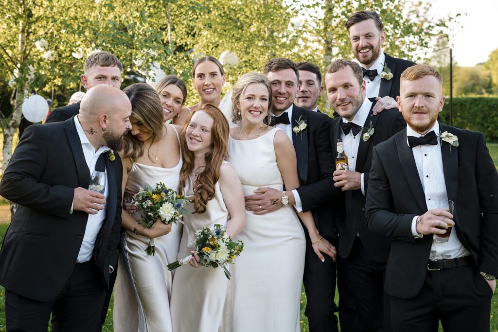 wedding party group photo laughing together in cotswold garden