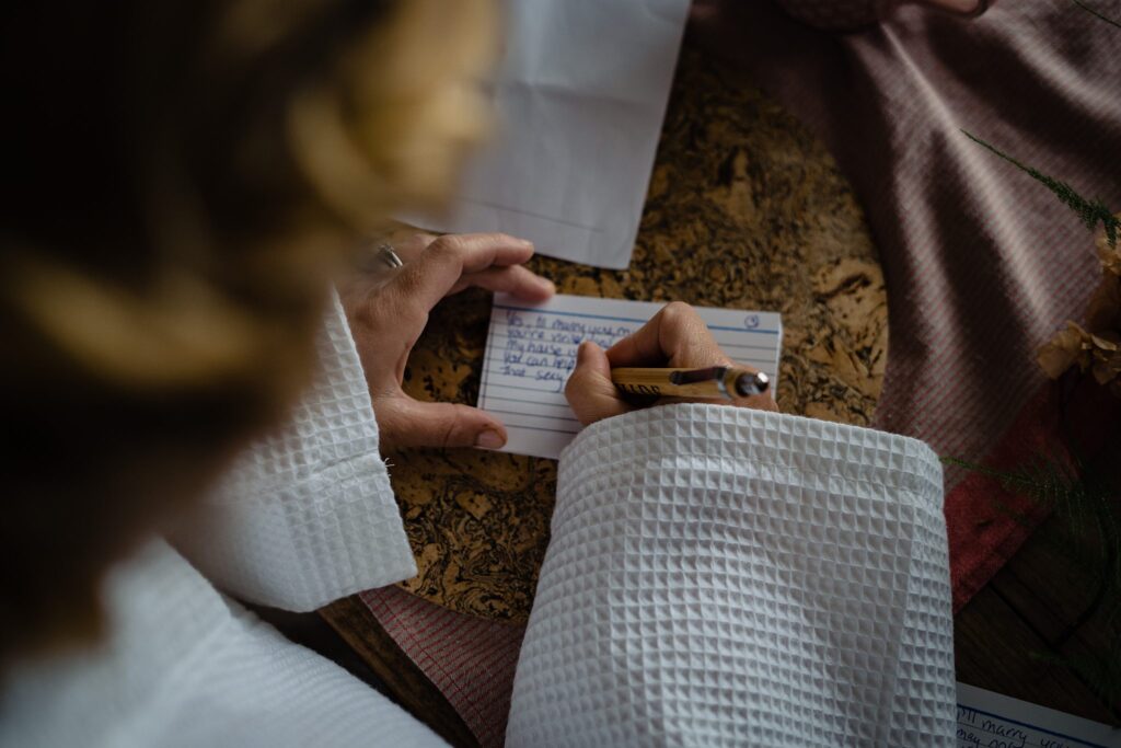 Bride writing wedding vows on a card during her Pauntley Court wedding morning