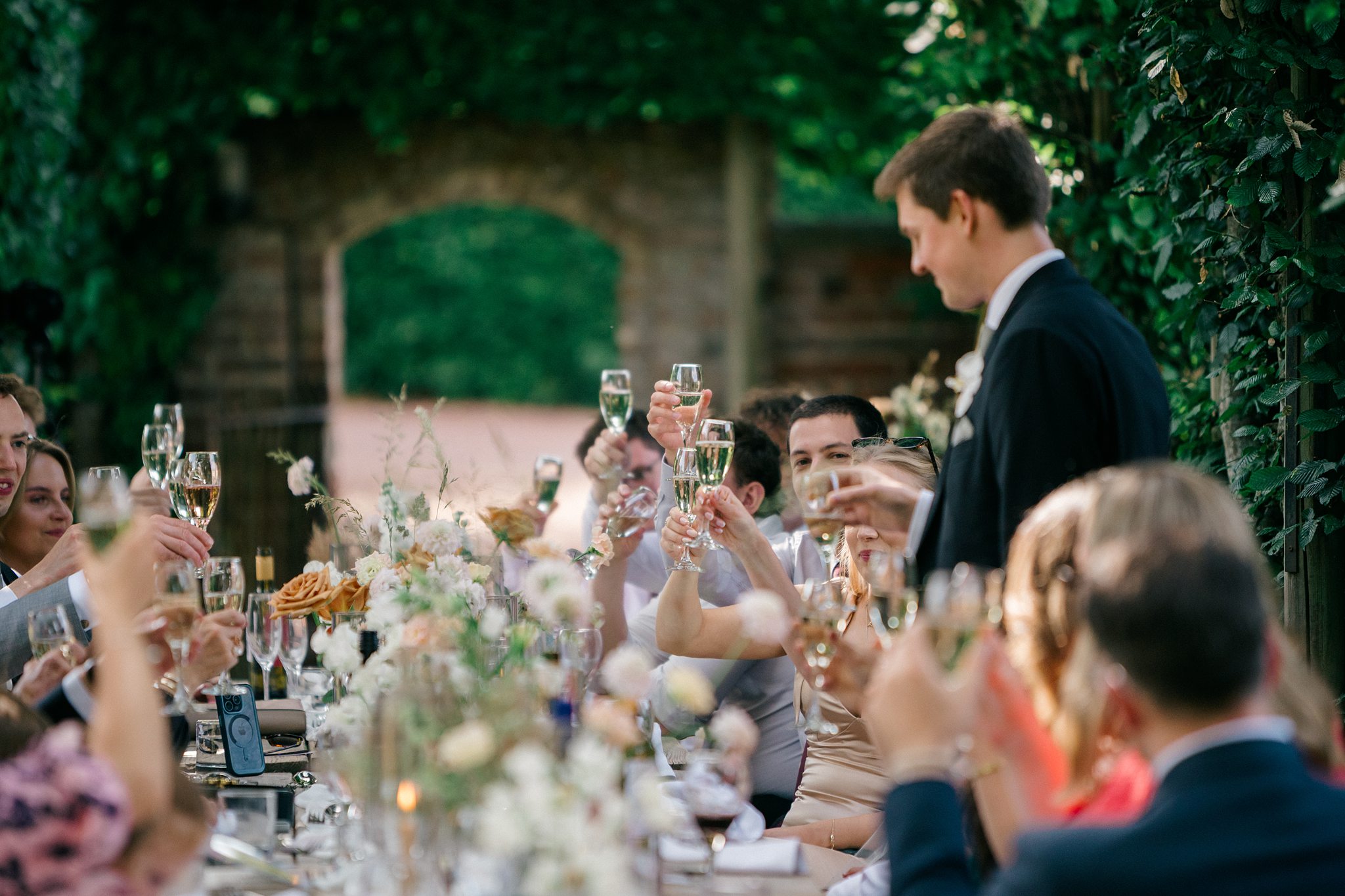 Guests raising glasses in a celebratory toast during wedding meal
