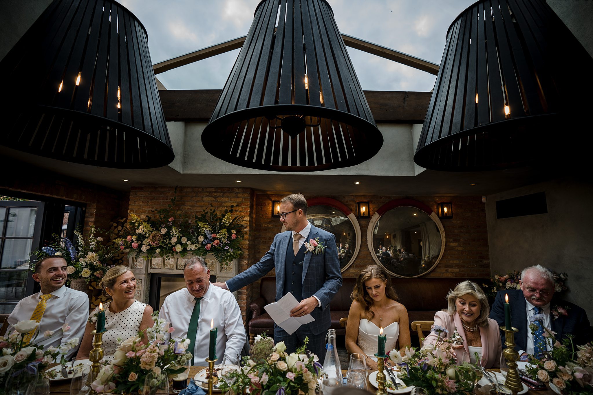 Groom gives wedding speech surrounded by family at No.131 Cheltenham reception.