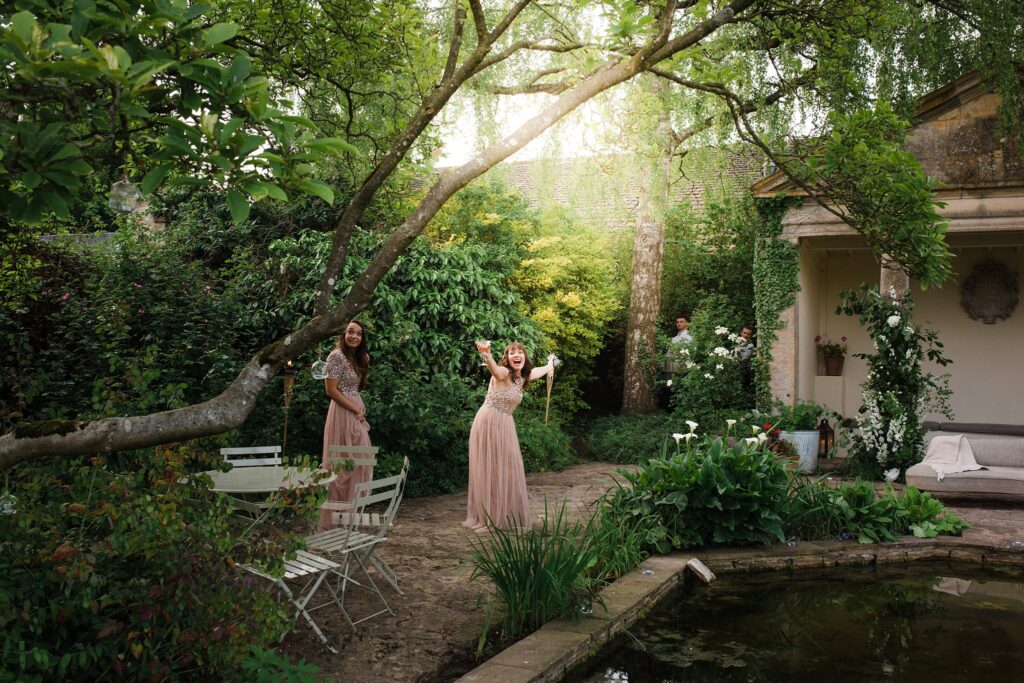 Bridesmaids laugh together in the leafy courtyard of Barnsley House.