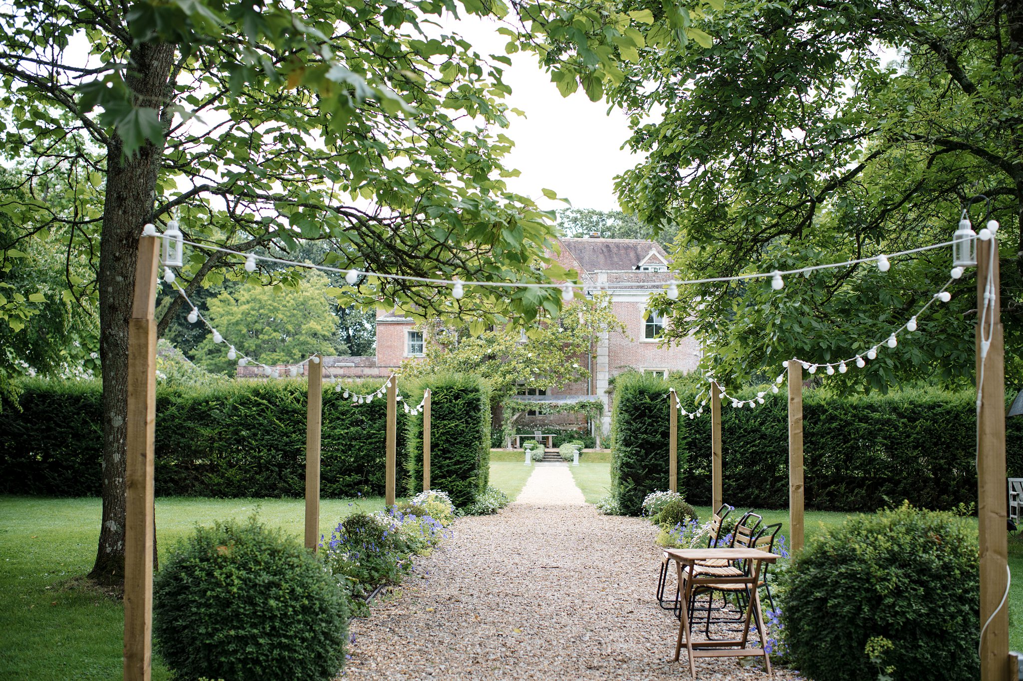 Festoon lit gravel pathway leading to the manor house at Deans Court Somerset