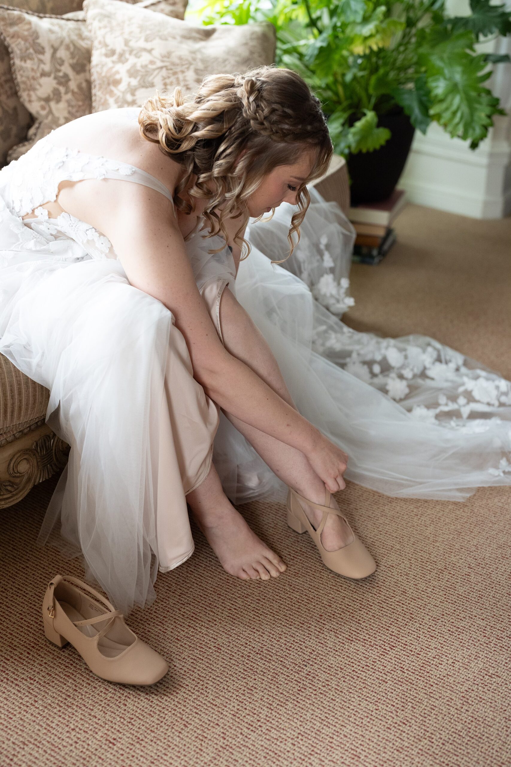 Bride fastening nude platform block heels with ankle strap shoes on wedding morning with wedding shoes for Gloucestershire weddings 